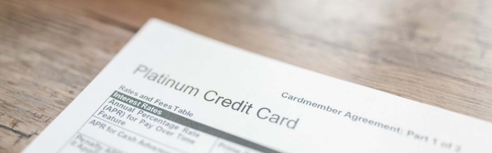 Close-up of a platinum credit card document with interest rates table on a wooden surface.