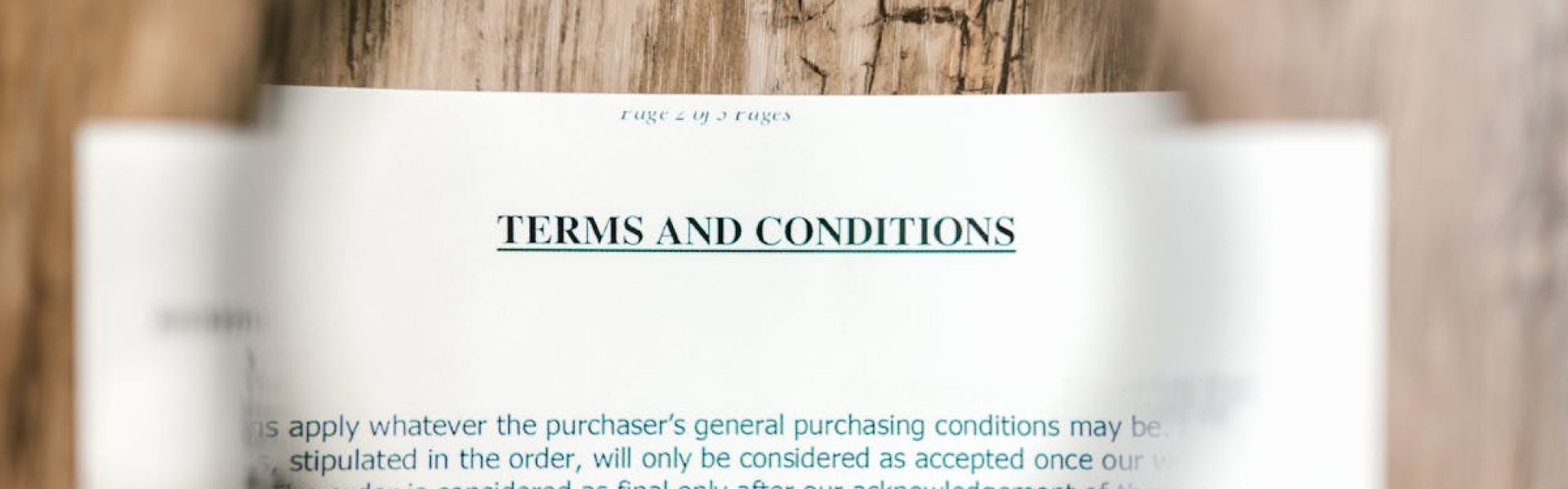 Magnifying glass focusing on terms and conditions document on wooden surface.